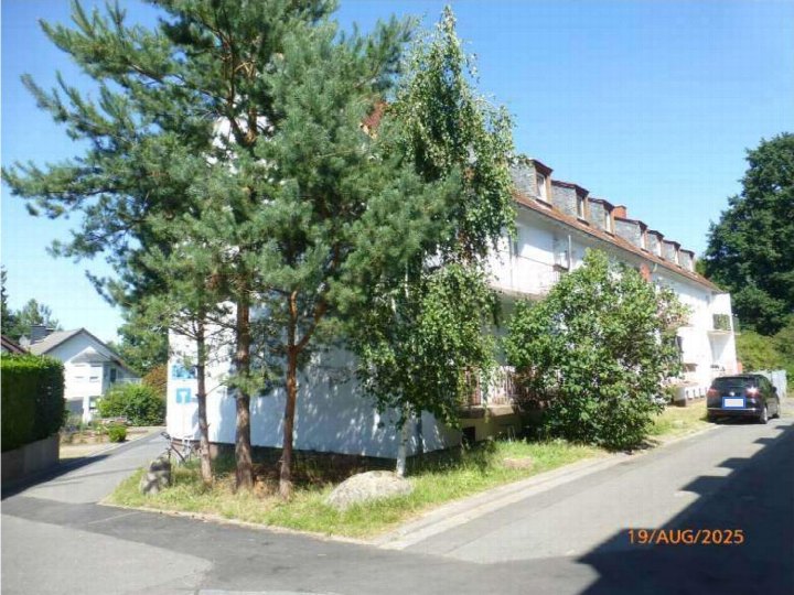 Seitenansicht eines Mehrfamilienhauses mit Bäumen, Grünfläche und Einfahrt in Messel, Marktstraße 25