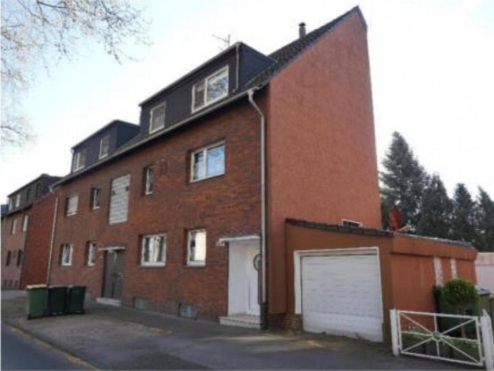Vorderansicht eines mehrstöckigen Backsteinhauses mit Eingang, Fenstern und Garagenanbau in Oberhausen, Neumühler Straße 115