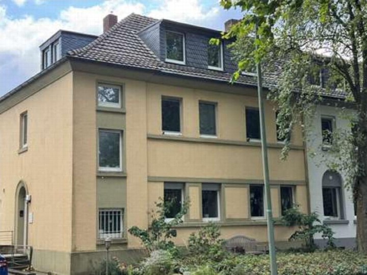 Gebäudeansicht der Wilhelmstr. 138 in Duisburg, 47198, mit gelber Fassade, Dachgauben und Eingangsbereich