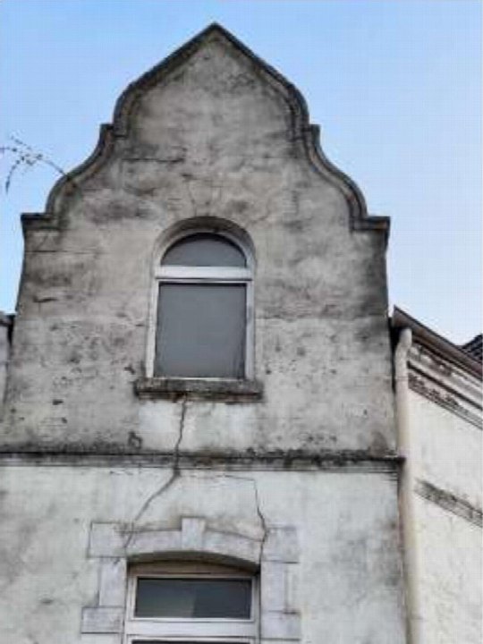Fassadendetail der Eigentumswohnung in Duisburg, Keithstraße 2, mit geschwungenem Giebel und Rissbildung im Putz