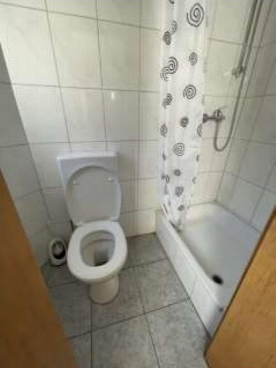 Badezimmer mit Toilette, Dusche und Fliesenwand, Teil eines Wohn-/Geschäftshauses in Duisburg