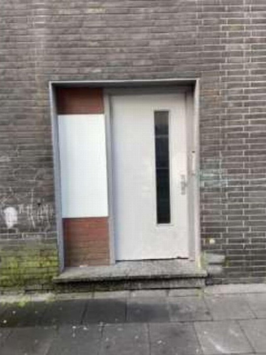 Eingangsbereich eines Gebäudes mit weißer Tür, grauer Ziegelwand und beigefarbener Seitenverkleidung in Duisburg