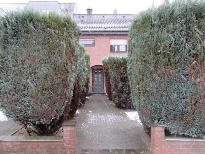 Zugangsweg zu einem Einfamilienhaus mit hohen Hecken und Eingangstür, leicht verschneit, in Duisburg
