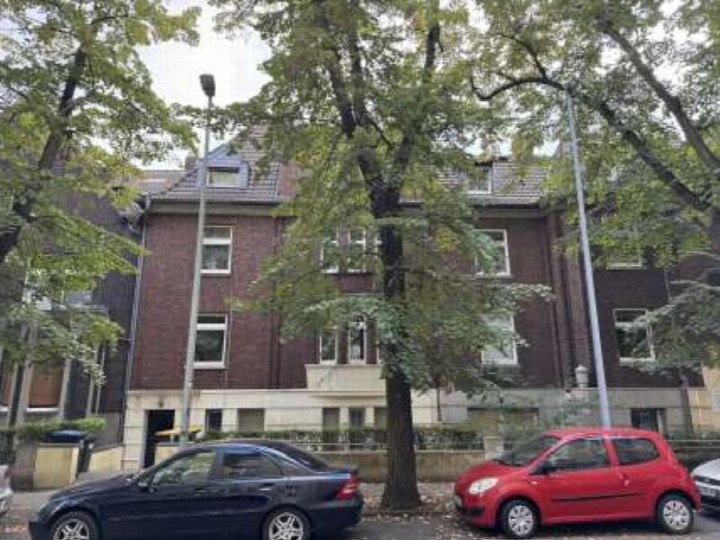Vorderansicht eines Mehrfamilienhauses in Duisburg, Elsa-Brandström-Str. 13, mit Bäumen und geparkten Autos vor dem Gebäude