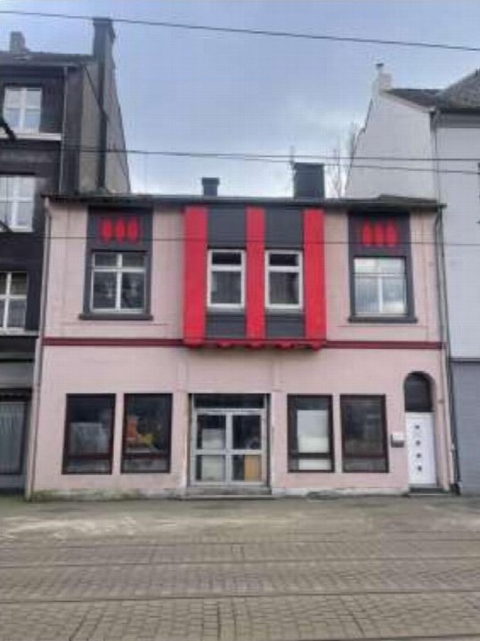 Vorderansicht eines zweistöckigen Wohn- und Geschäftshauses mit rosa Fassade, roten Akzentstreifen und Eingangstür in der Kaiser-Wilhelm-Straße 252, Duisburg