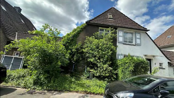 Vorderansicht eines Einfamilienhauses mit Satteldach, teilweise bewachsenen Wänden und Vorgarten in Duisburg, Franz-Wieder-Straße 7