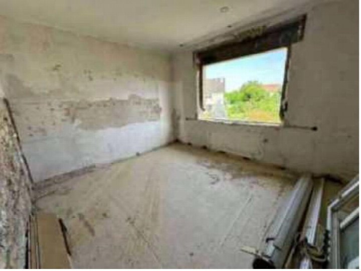 Unfertiger Innenraum mit Betonwänden und -boden, großem Fenster und Baustellenresten im Mehrfamilienhaus Donaustr. 21, Rödermark
