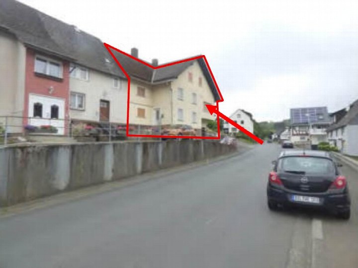 Seitenansicht eines mehrstöckigen Wohnhauses in Sinn-Fleisbach, Drosselweg 6, mit roter Umrandung des Gebäudes und Straßenszene im Vordergrund