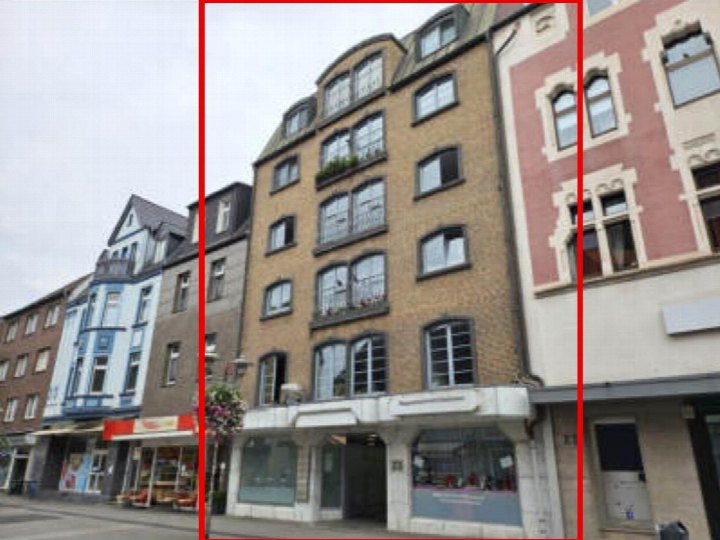 Fassade eines Wohn- und Geschäftshauses in Oberhausen, Bahnhofstr. 23, mit mehreren Stockwerken, Fenstern und Dachgauben