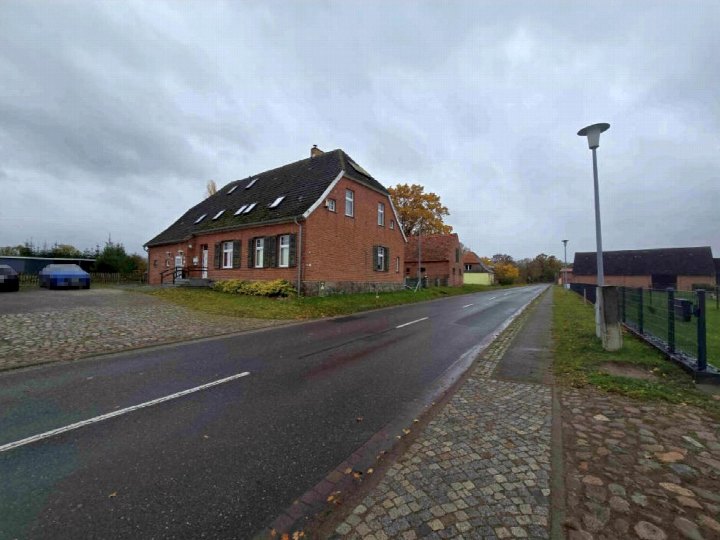 Einfamilienhaus aus Backstein mit Satteldach und Dachgauben an der Dorfstraße 4 in Sandhagen, Ansicht von vorne mit Straße und Vorgarten