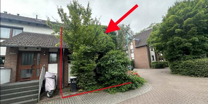 Eingangsbereich eines Reihenhauses mit Holztür, Stufen und angrenzender Grünfläche, Hausnummer 244a