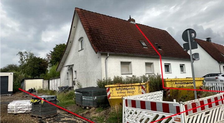 Seitenansicht eines Einfamilienhauses mit rotem Ziegeldach und weißer Fassade, umgeben von Baustellensicherung und Baustoffen in Duisburg, Maxstraße 16