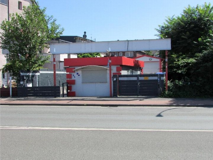 Garage mit rotem und weißem Anbau, schwarzem Tor und Überdachung, umgeben von Bäumen und Mauerwerk in Duisburg, Mannesmannstr. 49/49a