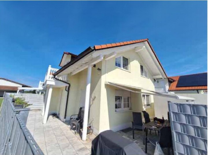 Terrasse mit Gartenmöbeln und Überdachung an einem hellen Einfamilienhaus mit rotem Ziegeldach in Hallbergmoos
