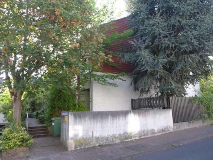 Seitenansicht eines Einfamilienhauses mit Betonmauer, Holzzaun und Bäumen, Tucholskystraße 65, Frankfurt am Main