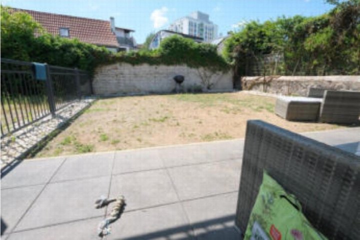 Trockener Gartenbereich mit Pflastersteinen, Steinmauer und Grünanlagen, umgeben von Gebäuden in Frankfurt am Main