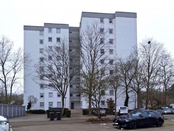 Frontansicht eines mehrstöckigen Wohnhauses mit Eingang, Fenstern und Bäumen im Vorgarten, Schlesier Straße 14, Limburgerhof