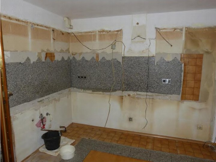 Badezimmer im Umbau mit abgebrochenen Wänden, sichtbaren Rohren und elektrischen Anschlüssen