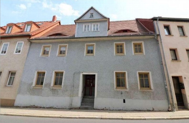 Fassade eines Reihenhauses in Merseburg, Unteraltenburg 17, mit grauer Putzfassade, Holzfenstern und rotem Ziegeldach
