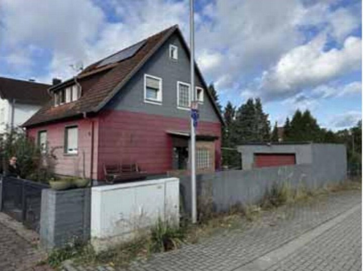 Einfamilienhaus mit grauem Obergeschoss und rotem Erdgeschoss, Satteldach, Fenstern und Eingangsbereich, gesehen von der Straße aus