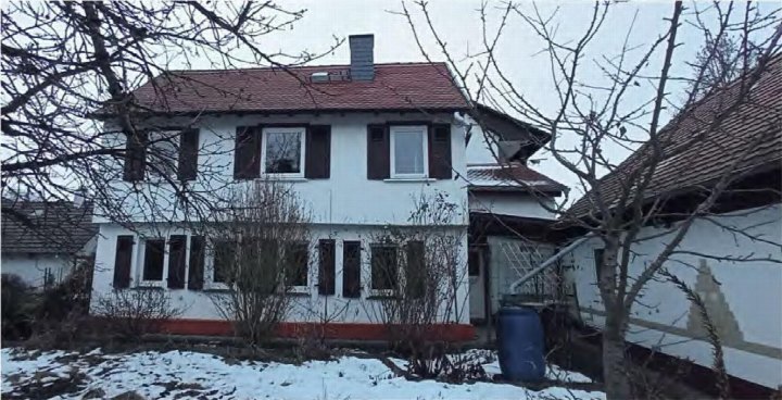 Zweistöckiges Einfamilienhaus mit rotem Ziegeldach und weißer Fassade, vorne gesehen, im Winter mit Schnee im Garten