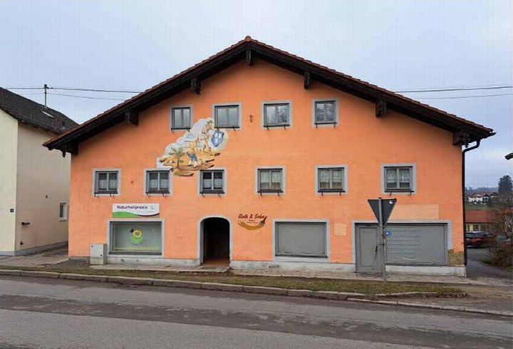Zweistöckiges Wohn- und Geschäftshaus in Orange mit Satteldach, Fenstern und Eingangsbereich an der Münchner Straße 32 in Isen