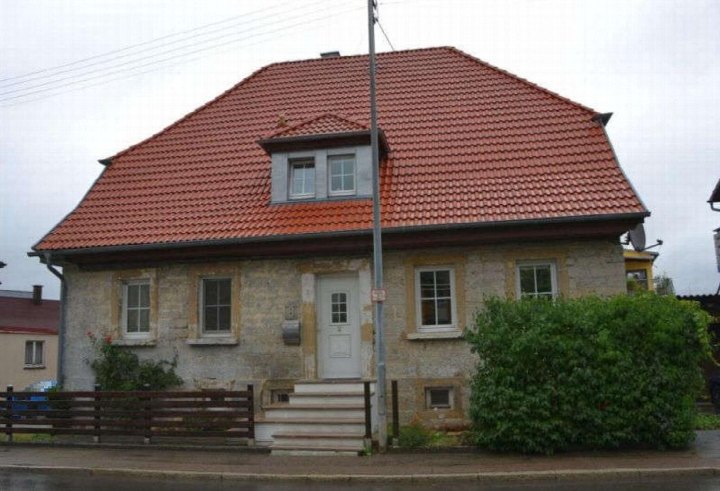 Einfamilienhaus mit rotem Ziegeldach, Steinmauerwerk und Vorgarten an der Kaiserstraße 8 in Blaufelden