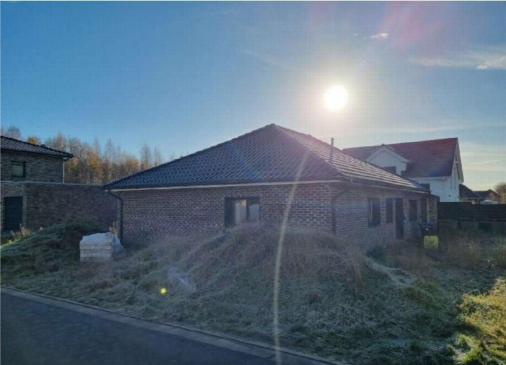 Einfamilienhaus aus Ziegelsteinen mit Satteldach, Seitenansicht mit frostbedecktem Garten und angrenzenden Gebäuden im Hintergrund