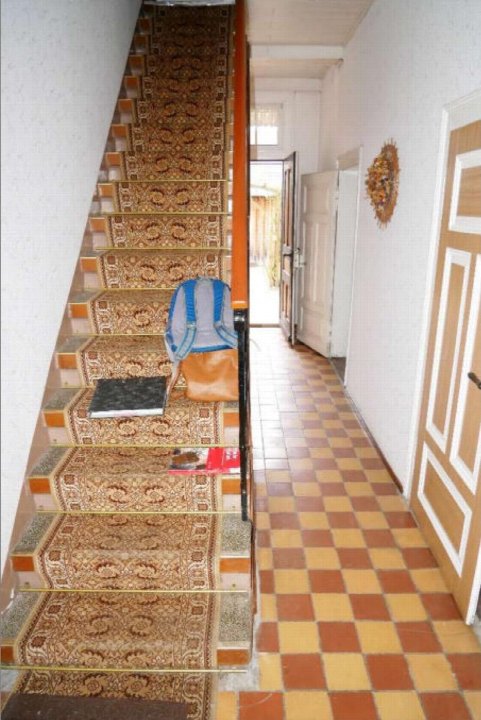 Treppenhaus mit gemustertem Teppichboden, Holzgeländer und Flur mit kariertem Fliesenboden im Zweifamilienhaus in Sömmerda