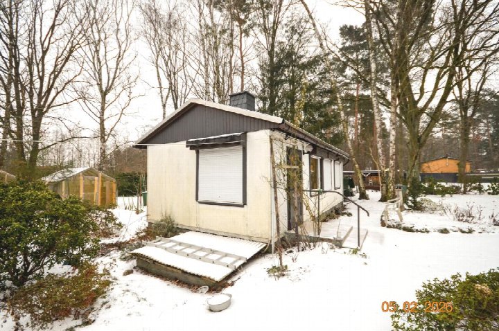 Schneebedeckter Garten mit kleinem Gebäude, Sträuchern und Bäumen in Oranienburg, Pfifferlingsweg