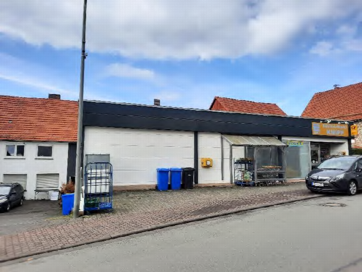 Außenansicht vorne eines gewerblich genutzten Gebäudes mit Ladenfront, Eingang, Mülltonnen und geparkten Fahrzeugen in Lichtenfels, Immighäuser Straße 4, 6