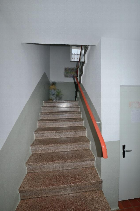Treppenhaus mit terrazzo-beschichteten Stufen, rotem Handlauf und weißen Wänden im Gebäude Schloßstraße 21, Neukieritzsch