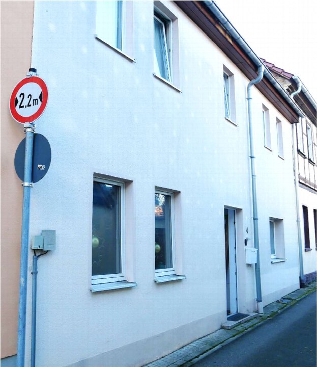 Seitenansicht eines weißen Reihenhauses mit Fenstern, Tür und Straßenverkehrszeichen, Rämenstraße 4, Sömmerda