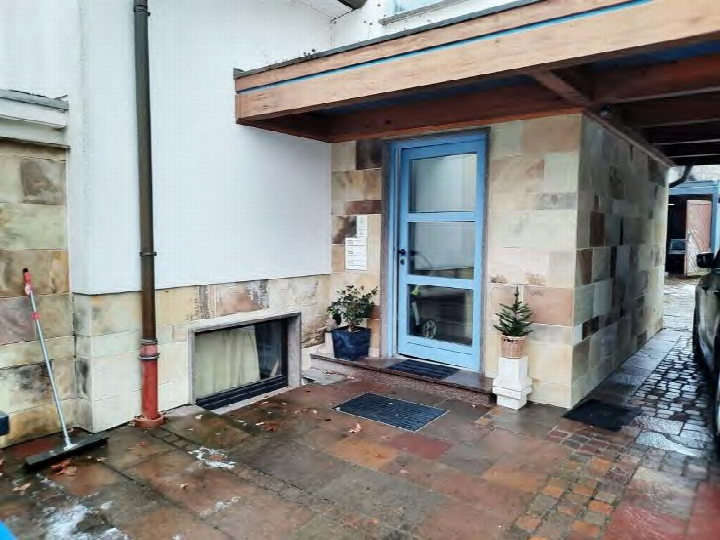 Eingangsbereich einer Eigentumswohnung mit blauer Tür, Steinverkleidung und Pflanzen im Vorgarten in Bad Arolsen