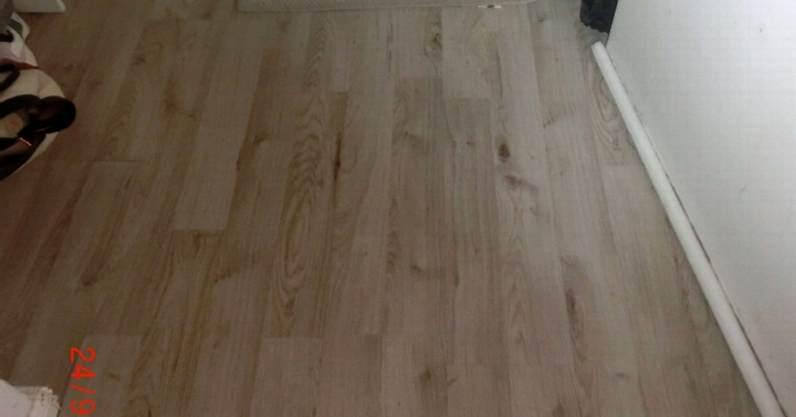 Holzboden in einem Innenraum mit sichtbarer Maserung und weißer Wandleiste