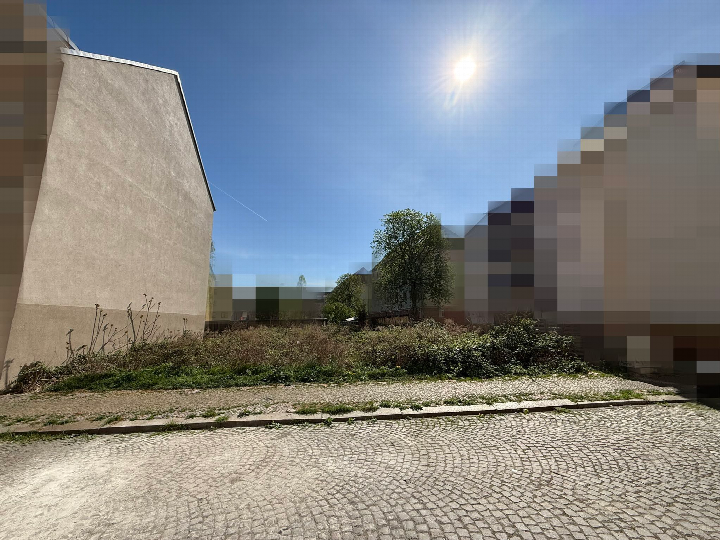 Unbebautes Grundstück mit Unkrautbewuchs, Kopfsteinpflaster und angrenzenden Gebäudewänden in Leipzig, Taubestraße 30