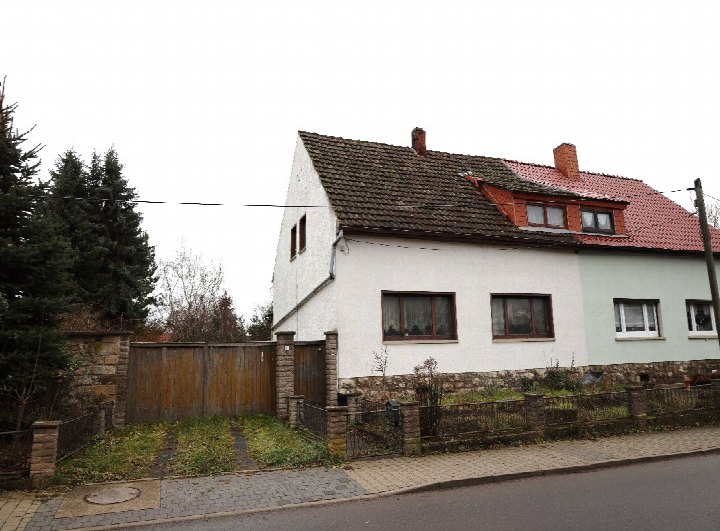 Fassade einer Doppelhaushälfte mit Satteldach, Fenstern und Gartenzaun an der Vargulaer Straße 10 in Tonna