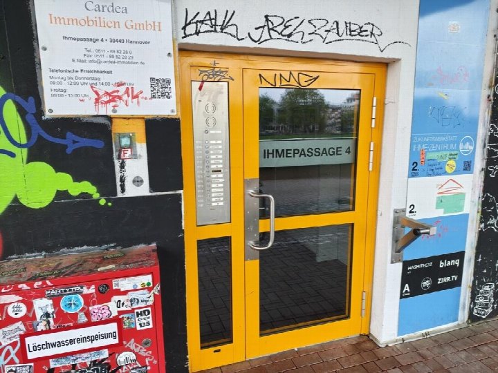 Eingangstür des Gewerbeobjekts Ihmepassage 4 in Hannover mit gelber Tür, Intercom und Schildern der Immobilienfirma Cardea