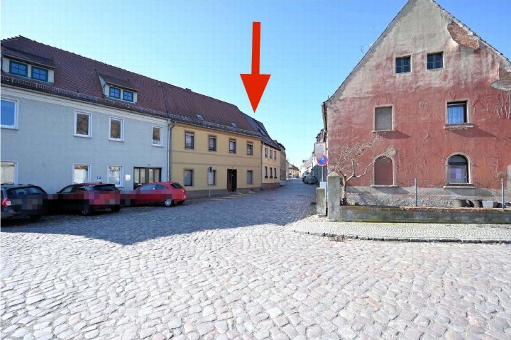 Straßenaussicht mit mehreren Gebäuden, darunter das Haus Reihzecher Straße 15 in Belgern-Schildau, markiert durch einen roten Pfeil