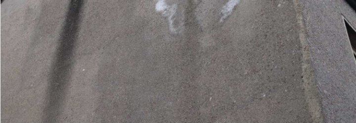 Nahaufnahme einer flachen Dachfläche mit sichtbarer Textur und weißen Flecken, vermutlich Beton- oder Asphaltdecke