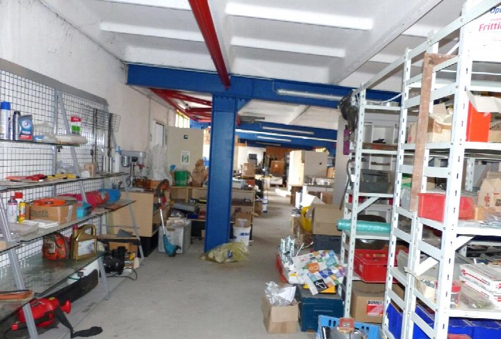 Innenraum eines Wohn-/Geschäftshauses mit Regalen, Werkzeugen und Lagerboxen, vermutlich Werkstatt- oder Lagerraum