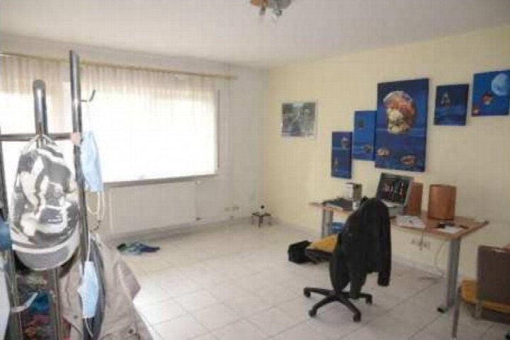 Innenraum mit Schreibtisch, Computer, Wandbildern und Kleiderständer, Fliesenboden, Fenster mit Vorhang