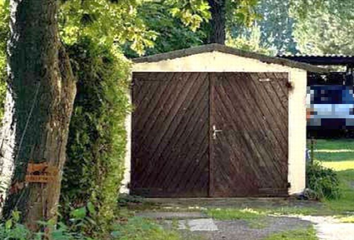 Holzschuppen mit Doppeltür im Gartenbereich, umgeben von Bäumen und Grünflächen
