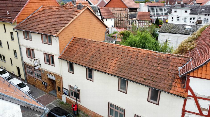 Seitenansicht eines Gebäudes mit rotem Ziegeldach und weißer Fassade in Eschwege, Hinter den Scheuern 2, umgeben von weiteren Häusern und Bäumen