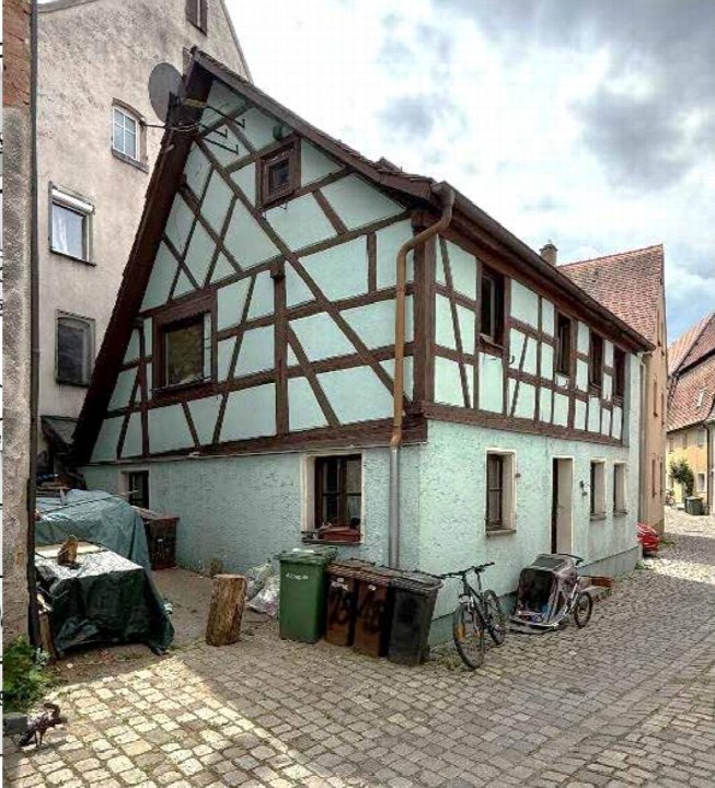 Seitenansicht eines Fachwerkhauses in der Gänsgasse 18, Spalt, mit sichtbaren Fenstern, Dach, Abwasserrohr und gepflastertem Hof