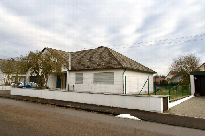 Seitenansicht eines Einfamilienhauses mit Satteldach, weißer Fassade, grünem Zaun und gepflastertem Vorplatz in Wittislingen, Juraweg 30