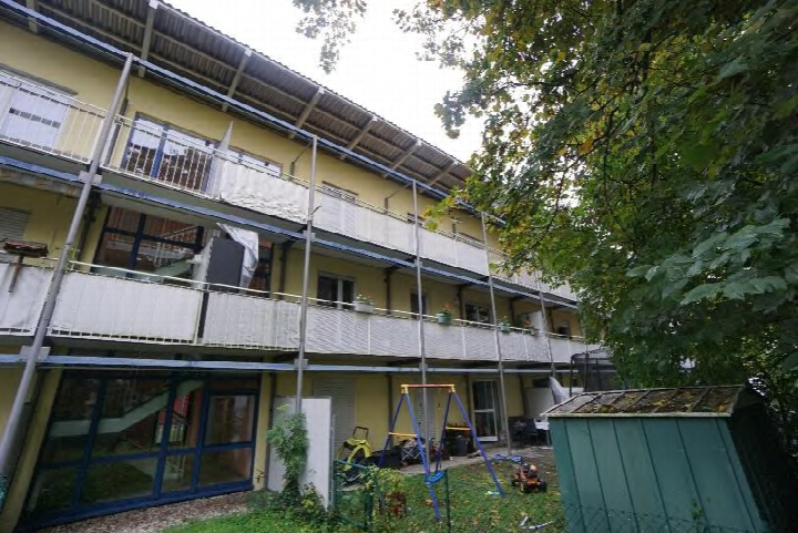 Hinterhof mit Grünfläche, Spielgeräten, Schuppen und Balkonen eines Mehrfamilienhauses in München, Smaragdstraße 10