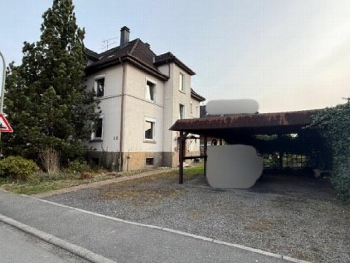 Zweifamilienhaus in Arnsberg, Rodentelgenstraße 14, mit Sicht auf die Vorderfassade, Dach, Fenster und angrenzenden Kiesplatz mit Carport