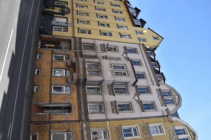 Fassade eines mehrstöckigen Gebäudes an der Trockentalstraße 84 in Plauen mit gelben und beigen Fassadenteilen und zahlreichen Fenstern