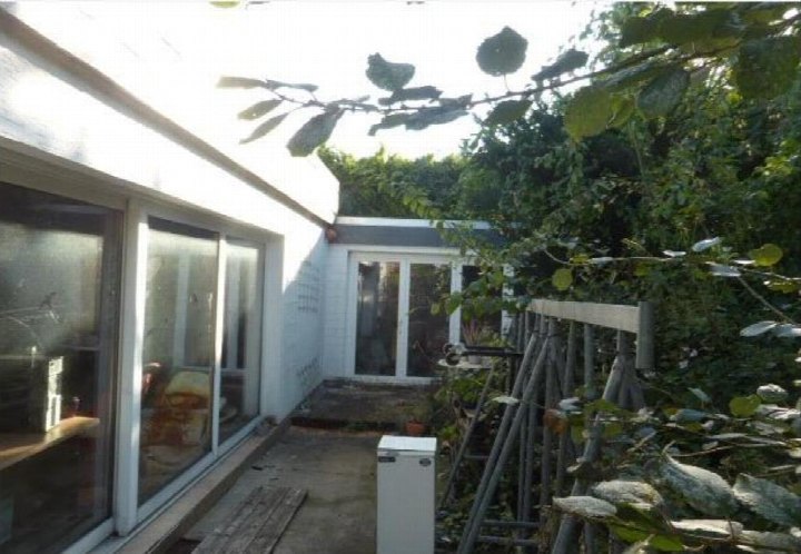 Gartenbereich mit Pflanzen, Metallzaun und Glasfront eines Einfamilienhauses in Paderborn, Scherfeder-Straße 23